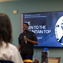 A male speaker addresses the crowd during the community dialogue.