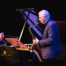 A man plays the saxophone while a pianist accompanies