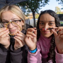 Two SUA students hold up the bonding bracelets they made during An SUA student gets her meal from the In-N-Out employee during SUA's annual Welcome Back Community Event 