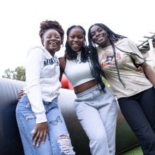 Three female students pose and smile during the Welcome Back event