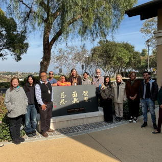 Writing Center staff gathered around a plaque titled "Wisdom, Courage, Compassion." 