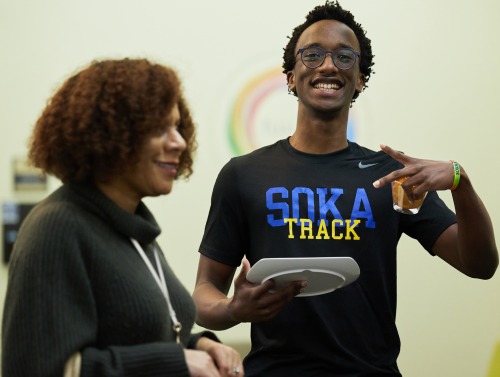 An SUA student wearing a Soka Track shirt smiles at the camera with Michelle Hobby-Mears smiling in the foreground