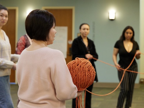 A woman holds a giant ball of yarn during an icebreaker exercise