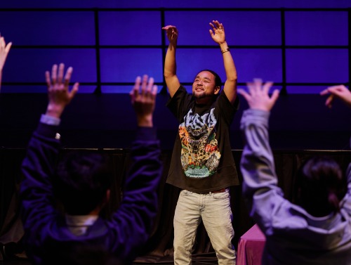 G Yamazawa raises his arms while performing during a DEI workshop