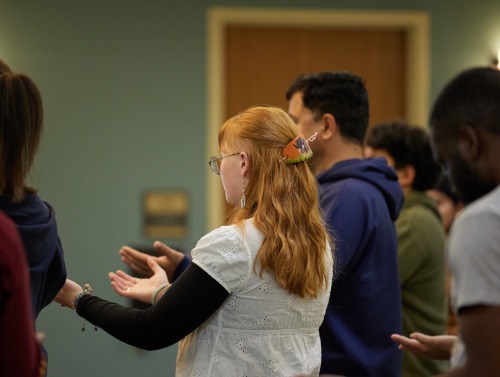 SUA students hold their arms out with their palms up during a DEI workshop