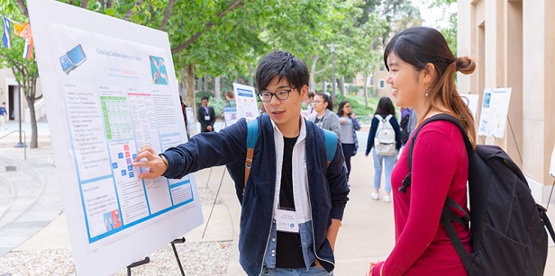 Students discuss findings at an easel displaying a poster