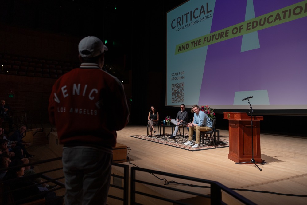 A student stands at a microphone and asks a question of the panel of speakers during a Critical Conversations event at SUA.