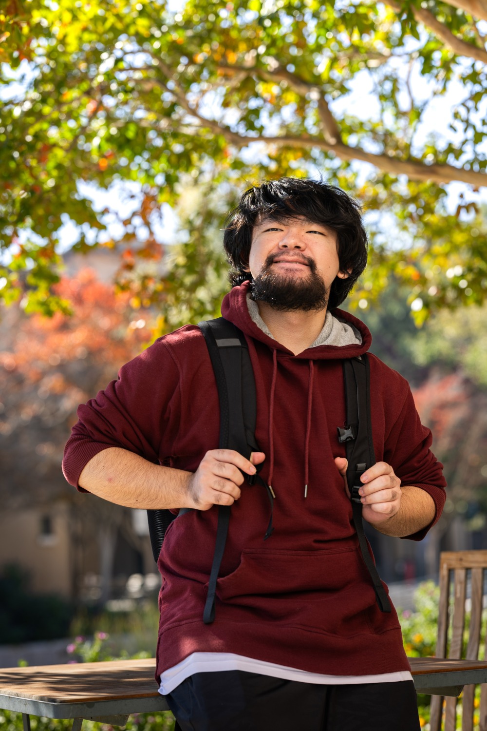 Kai Tomita holds his backpacks straps and smiles on SUA's campus.