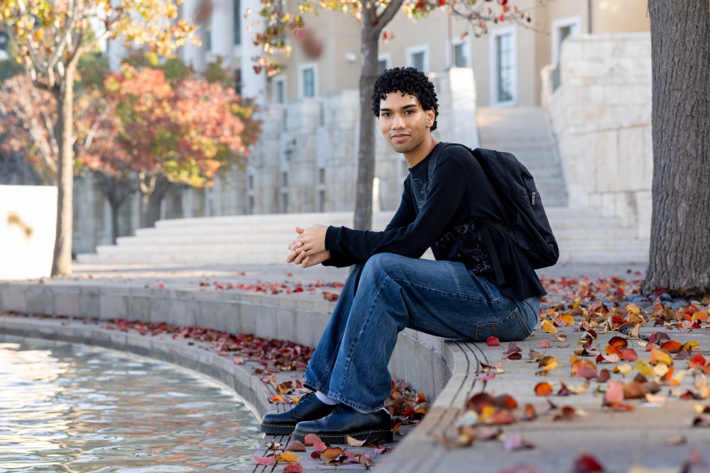 Chad Lutu sits on steps in front of Peace Lake.