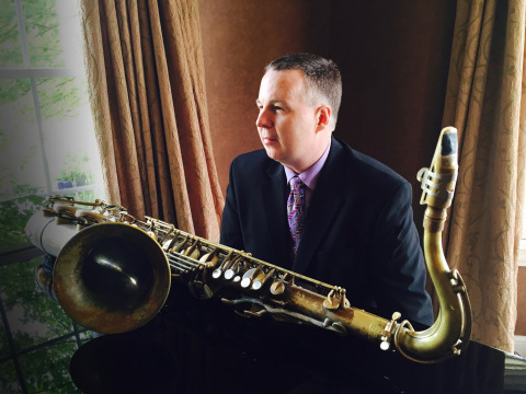 Harry Allen sitting an piano with saxophone