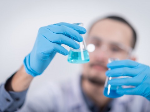 Person holding glass flasks in a lab