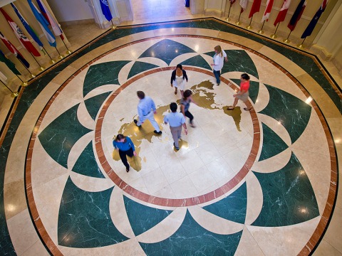 Students mingle on map of globe on the floor of Founders Hall