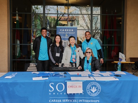 The Career Development and Internships Office team poses for a photo at their table outside the Bistro
