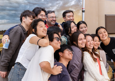 A large group of students and staff pose for a group photo in front of a backdrop during SUA's Homecoming celebration.