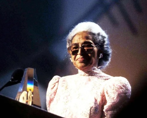 Rosa Parks stands at a podium